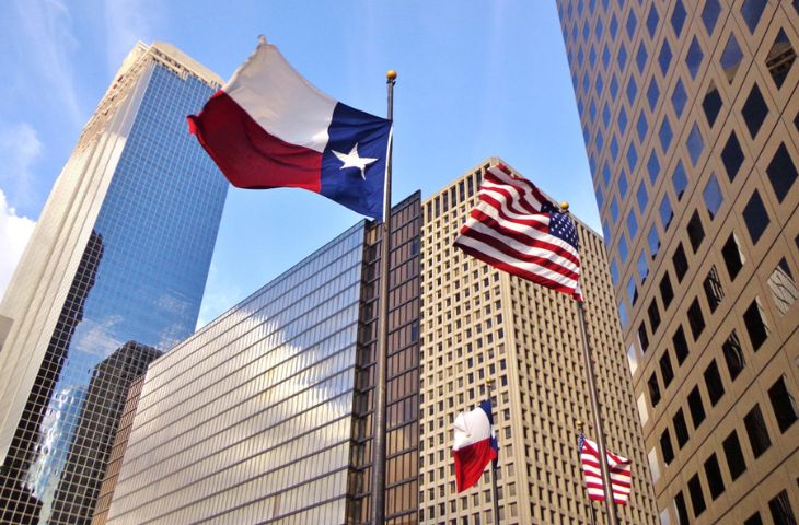 The Texas flag and the USA flag flying in a downtown Houston business district.